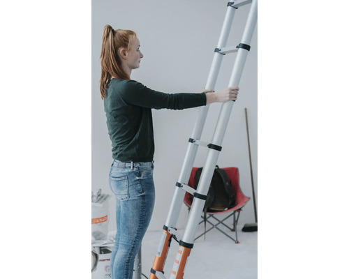 Kvinna håller en teleskopstege i ett rum.