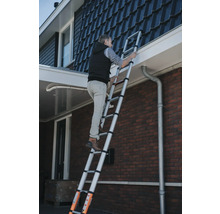 Man klättrar på en teleskopisk stege mot ett hus