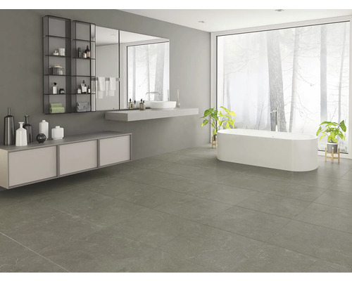 Modernt badrum med badkar, handfat, spegel, hylla och grått golvkakel