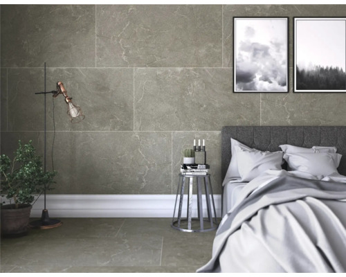 Sovrum med vägg- och golvplattor i stenlook, säng och dekorationer.