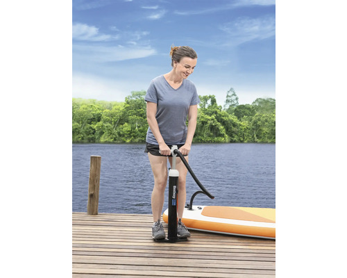 Kvinna pumpar upp en stand-up paddleboard med en handpump på en träbrygga