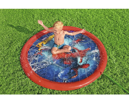 Pojke sitter i en rund vattenspridare på gräsmatta