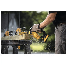 Person sågar trä med en batteridriven motorsåg från Dewalt