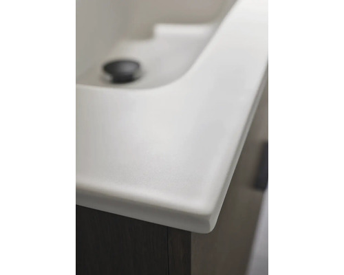 Detaljvy av ett vitt tvättställ med ett mörkt underskåp