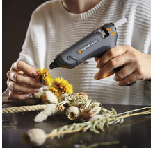 Användare fixerar blommor på en krans med en limpistol