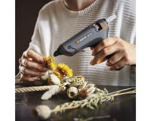 Användare fixerar blommor på en krans med en limpistol
