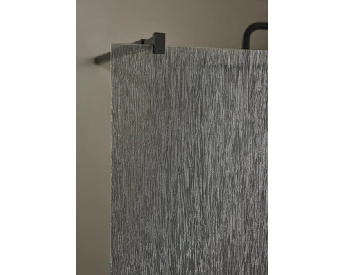 Närbild av duschvägg med strukturerat glas och svarta beslag