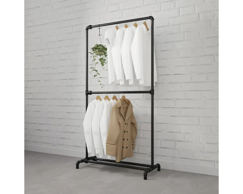 Svart klädställning av metallrör med kläder och växt