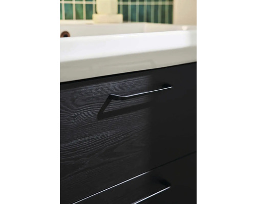 Närbild av ett svart tvättställsskåp med lådor och handtag i badrummet.