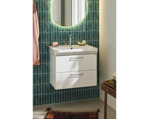 Badrum med tvättställsskåp, spegel och armatur framför en vägg med kakel