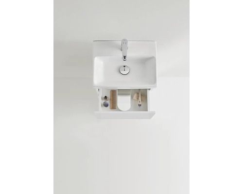 Överifrån av ett handfat med öppen låda och badrumsartiklar