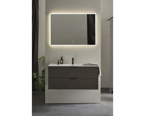 Badrum med tvättställsskåp, tvättställsskål, armatur och belyst spegel