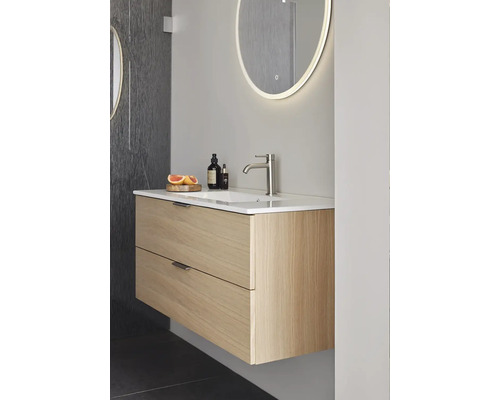 Badrum med tvättställsskåp i trä, handfat, blandare och belyst spegel