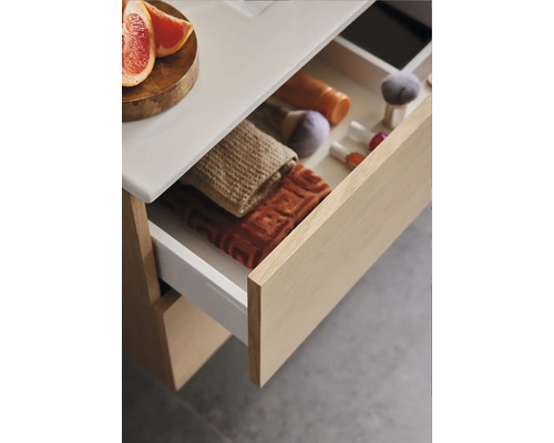 Badrumsskåp med öppen låda, handdukar och toalettartiklar