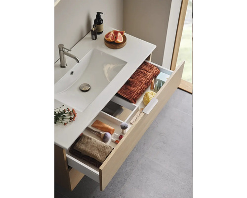 Badrum med handfat, tvättställ och öppna lådor för förvaring av handdukar och kosmetiska produkter