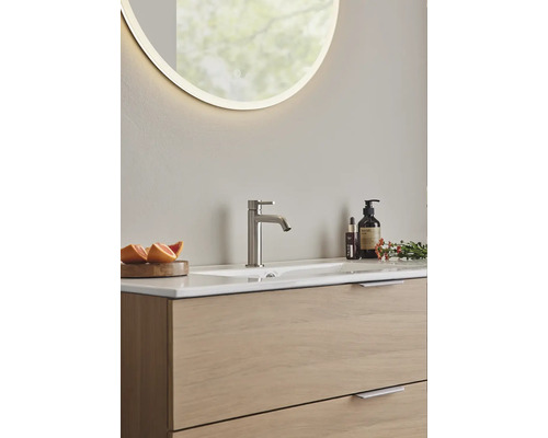 Modernt badrum med tvättställsskåp, ovanpåliggande tvättställ och upplyst spegel