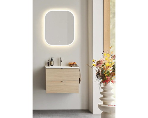 Badrum med tvättställsskåp, tvättställ och belyst spegel för en ljus och organiserad atmosfär.