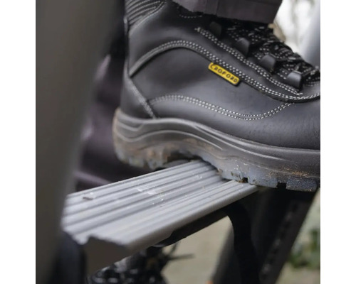 En fot i en skyddssko på ett steg på en stege.