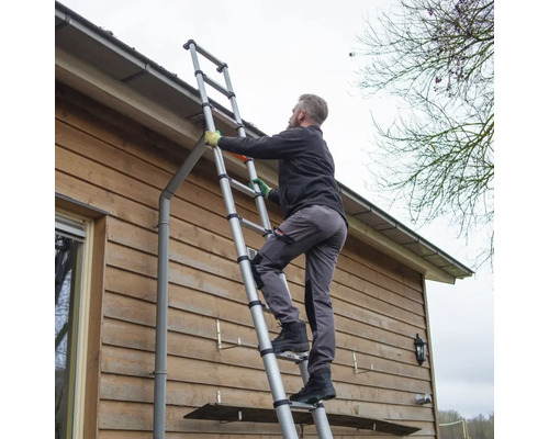 En person klättrar på en teleskopisk stege mot en husvägg.