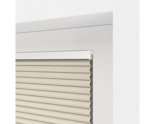 Detaljvy av en beige plisségardin i en fönsterkarm.