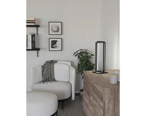 Ljust vardagsrum med fåtölj, sidobord och dekorationer