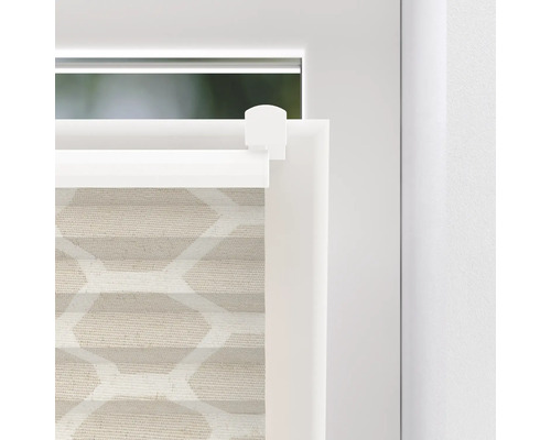 Detalj av en beige plisségardin med geometriskt mönster vid fönstret