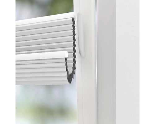 Närbild av en vit plisségardin på fönstret