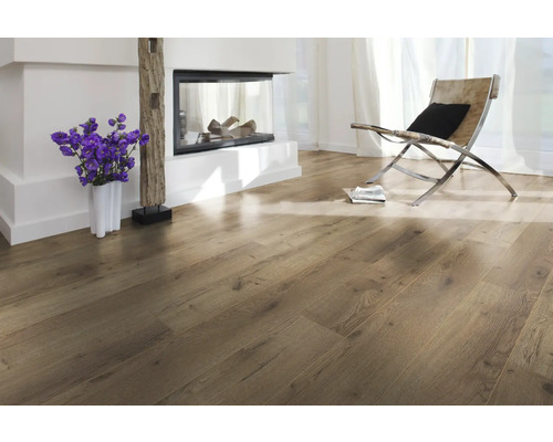 Ljust rum med trägolv, öppen spis och fåtölj