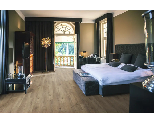 Sovrum med säng, skåp, golvlampa och balkong med utsikt över en park.