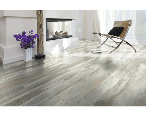 Ljust rum med öppen spis, fåtölj och laminatgolv i trälook