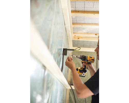 Elektriker installerar en infälld dosa med en batteridriven skruvdragare i en vägg.