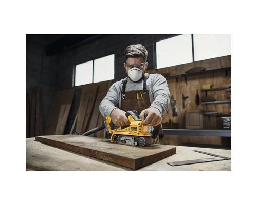Man slipar trä med en DeWalt bandslipmaskin i en verkstad.