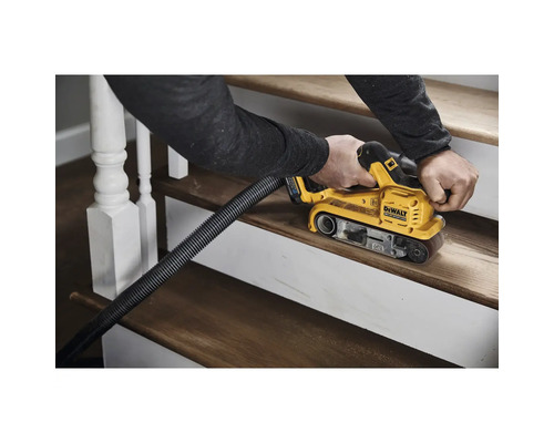 En person slipar en trätrappa med en bandslipmaskin. Damm avlägsnas med ett utsugssystem.