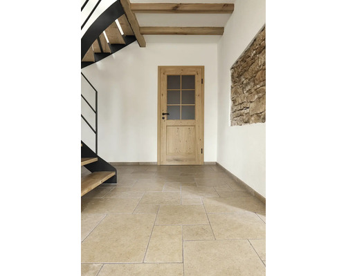 Interiör med trätrappa, träbjälkar, trädörr och stengolv