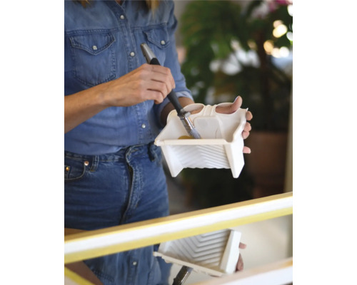 Kvinna doppar pensel i ett färgtråg