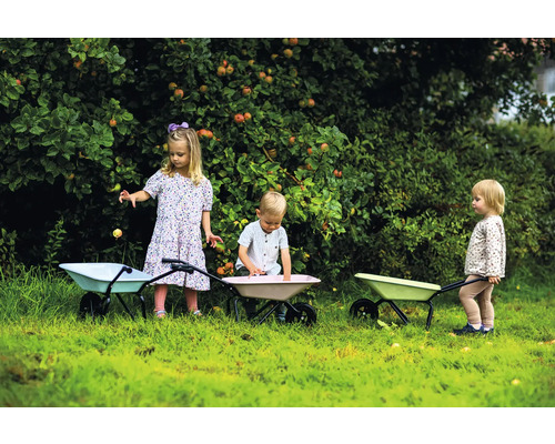 Scen med tre barn som leker i trädgården med skottkärror