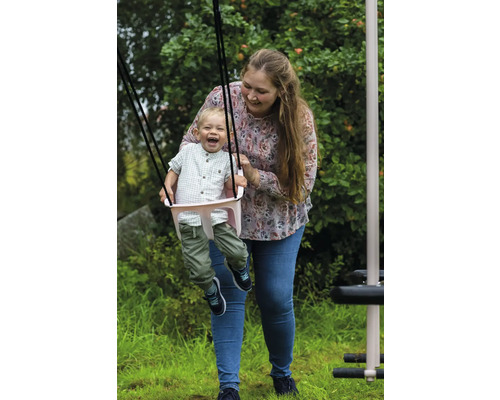 En kvinna skjuter ett barn på en babysvinga i trädgården.