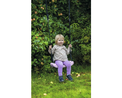 Ett barn gungar på en trädgårdsgunga framför ett äppelträd.