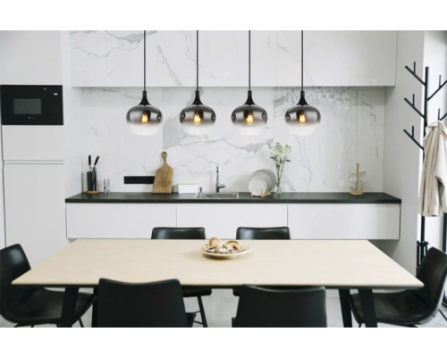 Matbord med fyra stolar och pendellampor i ett ljust kök