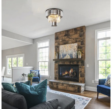 Vardagsrum med taklampa i kristallstil ovanför en öppen spis i sten