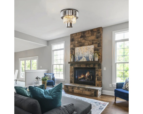 Vardagsrum med taklampa i kristallstil ovanför en öppen spis i sten