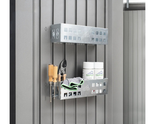 Två metallhyllor med verktyg, rengöringsdukar och sprayburkar på en vägg