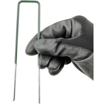 En hand med trädgårdshandske håller en grön gräsmatta spik.