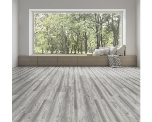 Ljust rum med grått trägolv, fönsterbräda med kuddar och utsikt över grönska