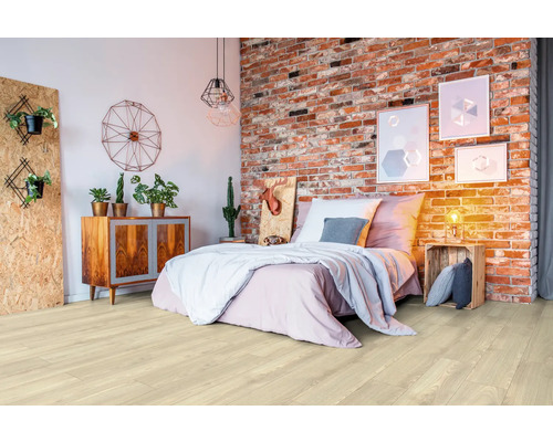 Ljust trägolv i ett sovrum med säng och tegelvägg