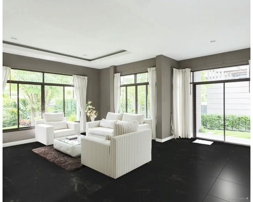 Vardagsrum med svarta golvplattor, vita möbler och stora fönster.
