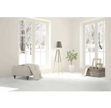 Ljust rum med utsikt över snöiga träd, pall, golvlampa och dekoration