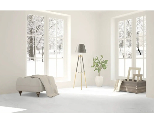 Ljust rum med utsikt över snöiga träd, pall, golvlampa och dekoration