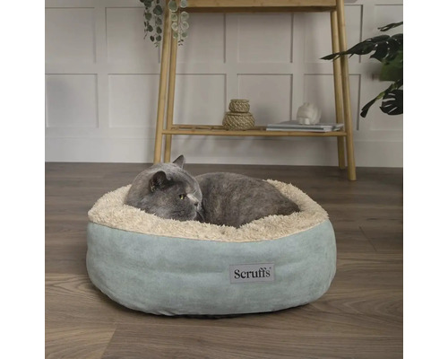 Grå katt ligger i en rund, mjuk kattsäng av märket Scruffs