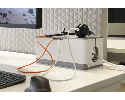 Kabelbox på ett skrivbord med hörlurar och elektroniska apparater för kabelhantering